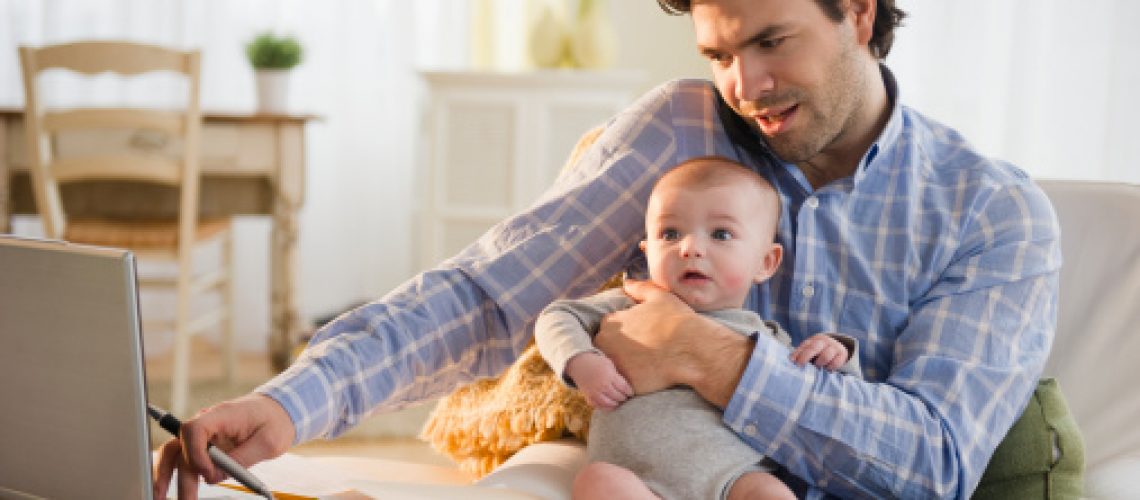 Father holding baby while working